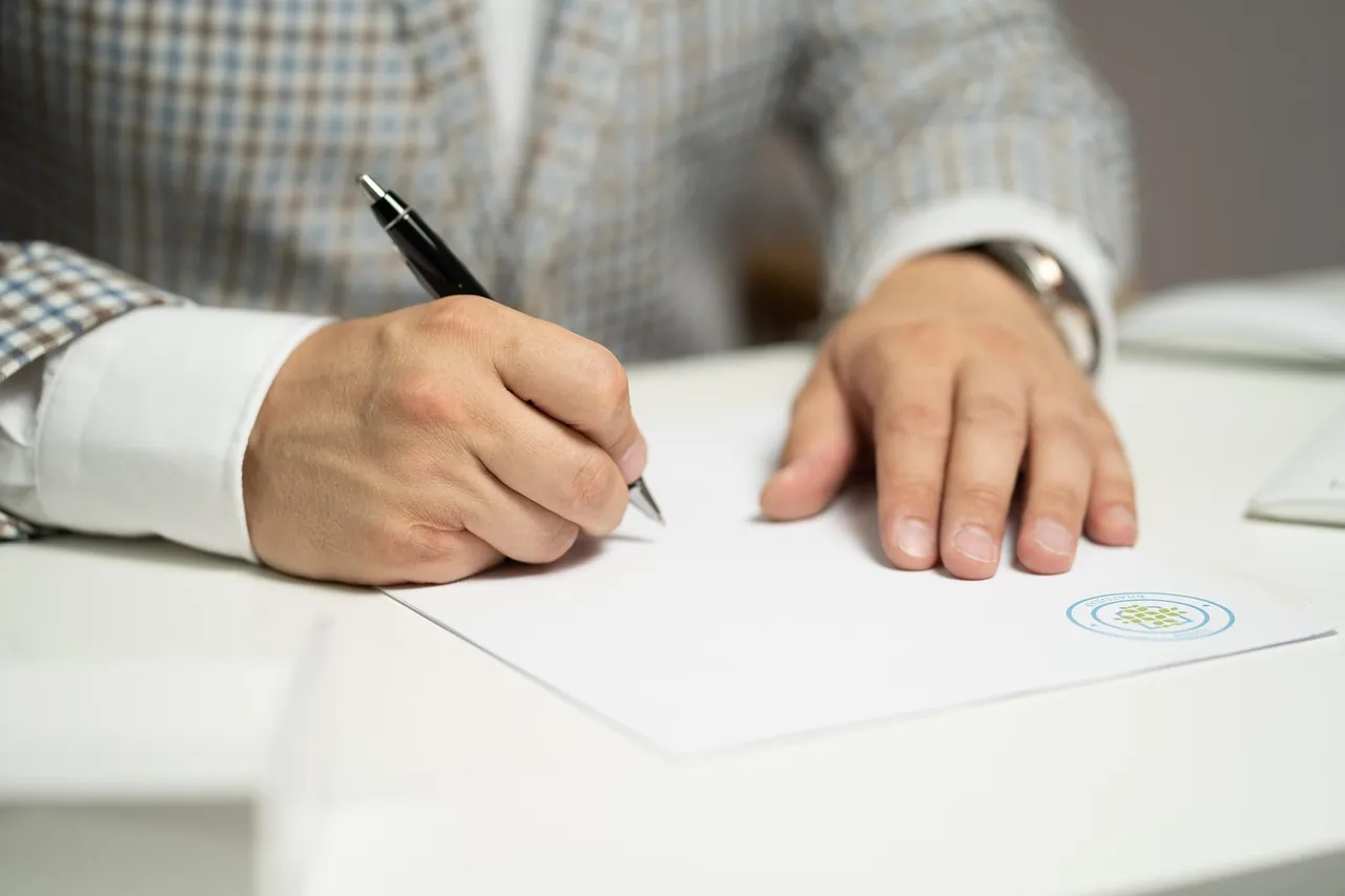 Un client signe un document à son bureau, dans le cadre d'une démarche de changement de banque
