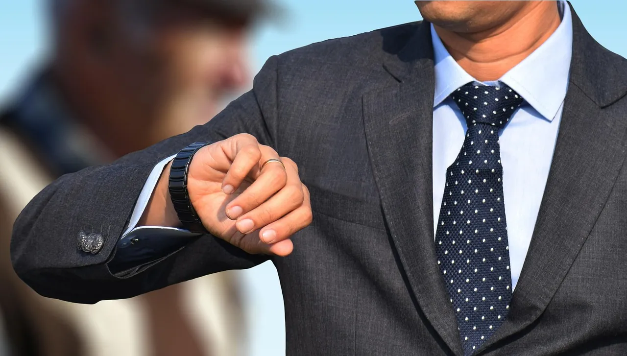 Homme en costume consultant sa montre au poignet, à l'extérieur en pleine lumière du jour