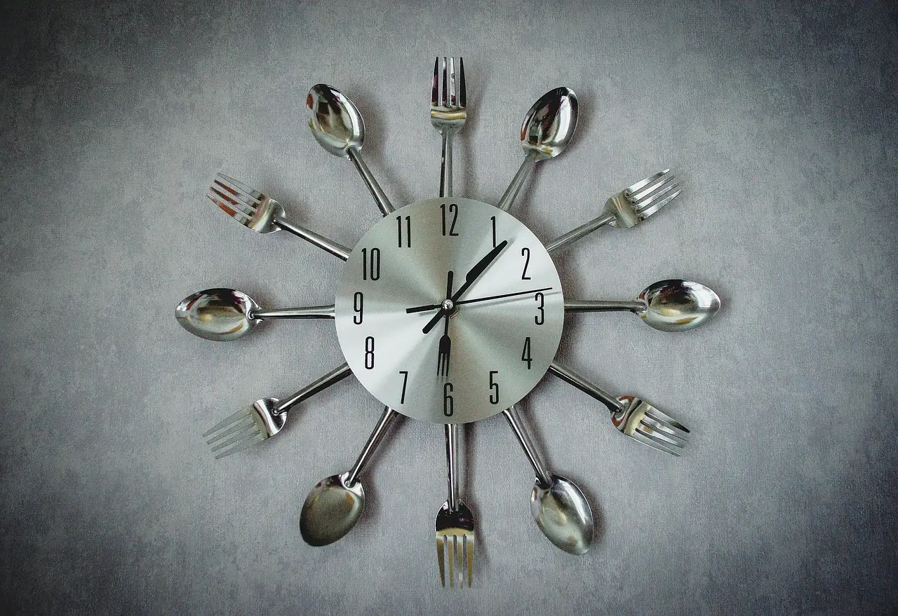 Horloge murale composée de fourchettes et de cuillères, symbolisant l'alternance entre fenêtre alimentaire et fenêtre de jeûne