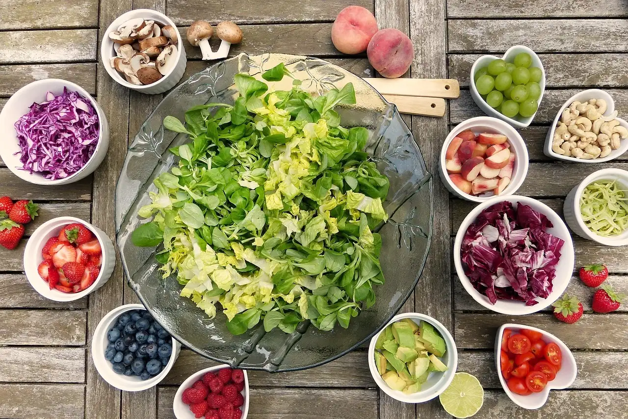 Assortiment de légumes verts à feuilles, de fruits et d'oléagineux disposés sur une table, sources alimentaires de magnésium