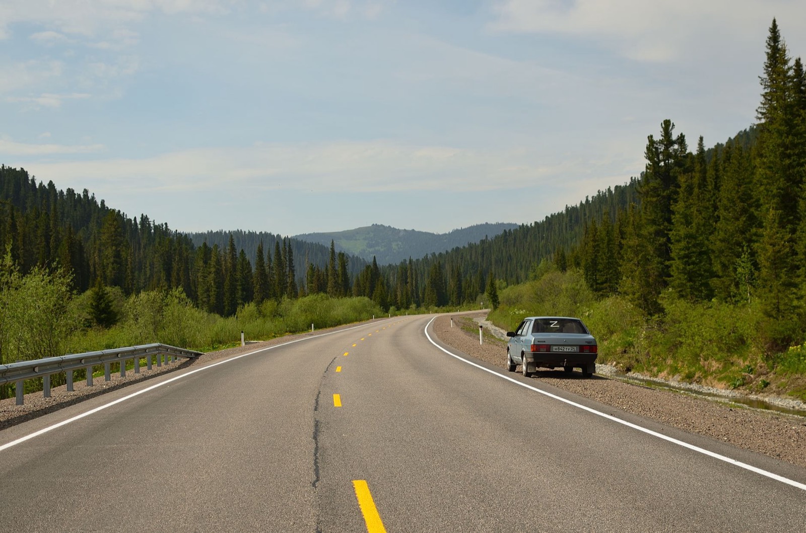 Route de campagne entourée de collines verdoyantes typiques d'un road trip en Auvergne